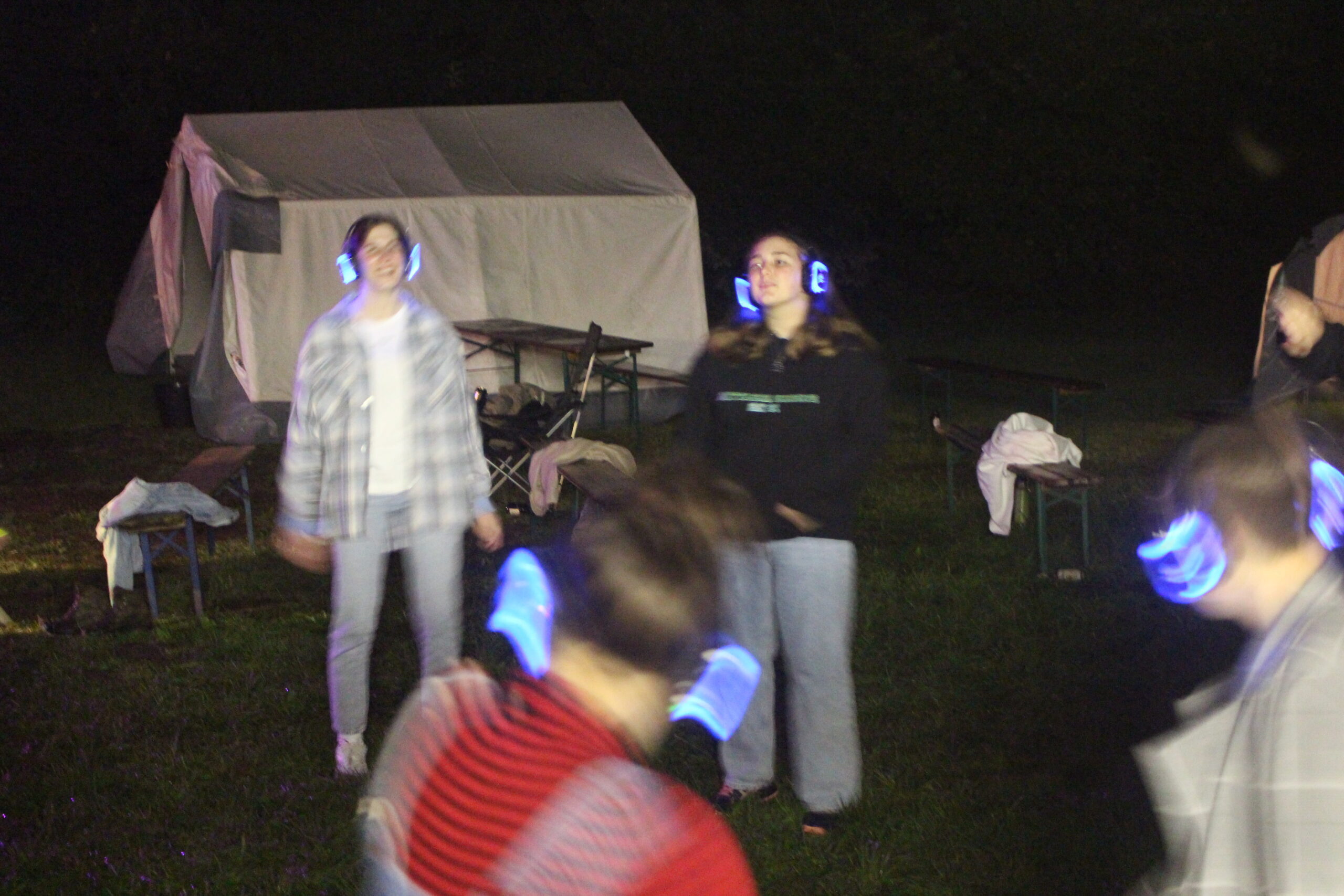 Menschen auf einer Wiese tragen Kopfhörer von Silent Disco.